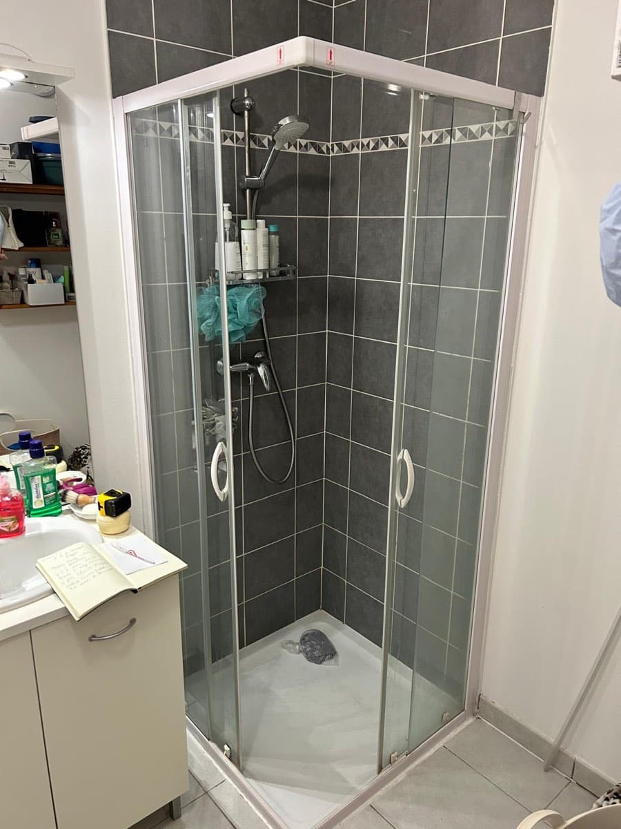 Avant : ancienne cabine de douche d'angle avec receveur haut et carrelage gris — FPC Lyon